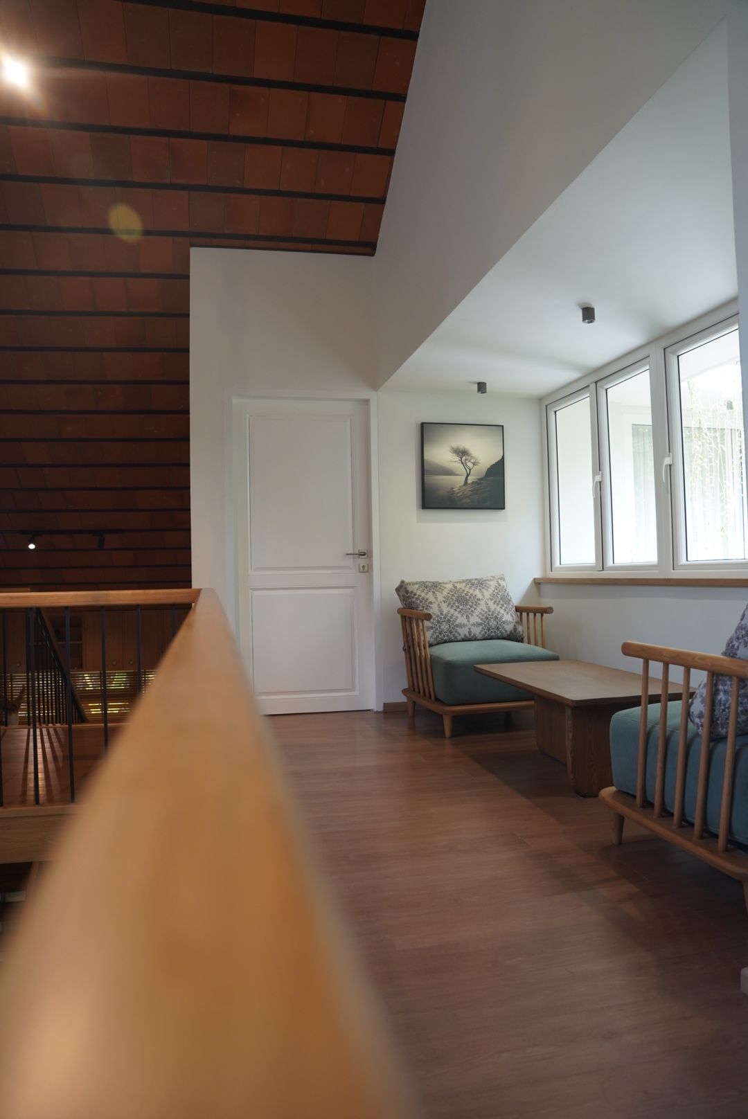 Landing sitting area by ALTICA with timber armchairs, a low table and a band of windows